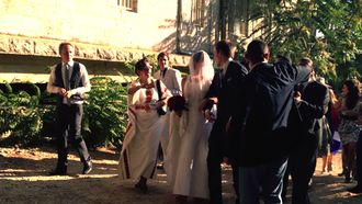 A group of people in festive clothing surrounding a couple on their wedding.