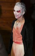 A person with white make-up with blood spatter in their face.